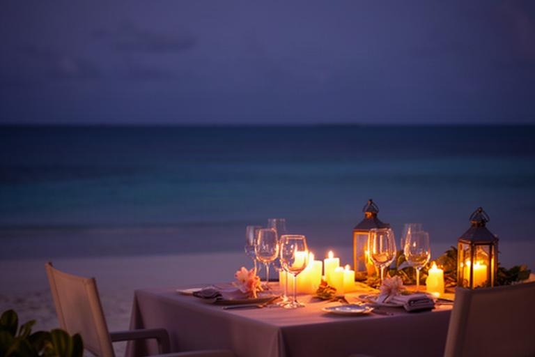 Candlelit dinner for two on a Caribbean beach at dusk